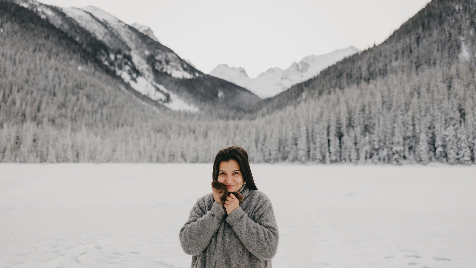 A woman holding up Aurora Heat hand warmers on a mountain covered in snow.