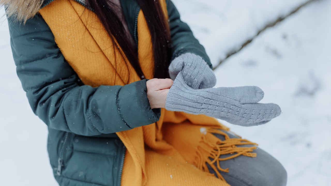 A lady putting on mittens with hand warmers for cold hands