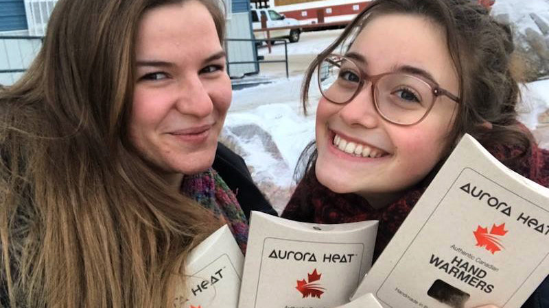 Two women holding up Aurora Heat retail products