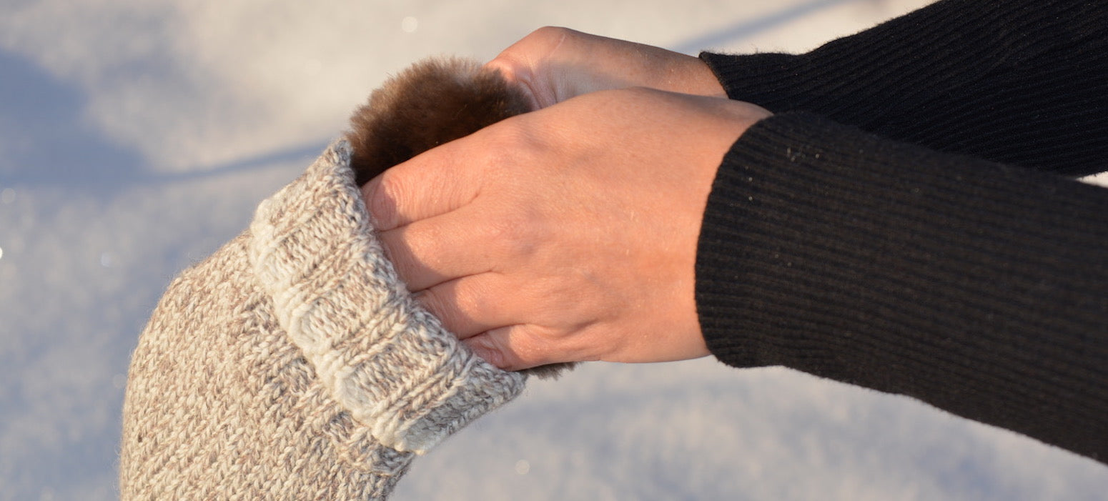 A person slipping their hand into their mitten with Aurora Heat's reusable hand warmer to fight the cold.