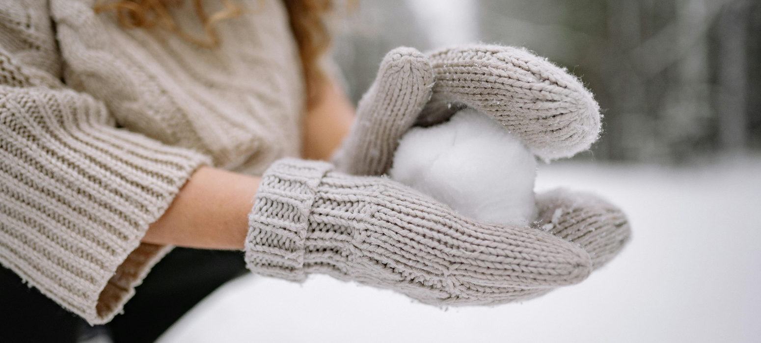 Women making a snowball with mittens and hand warmers on.