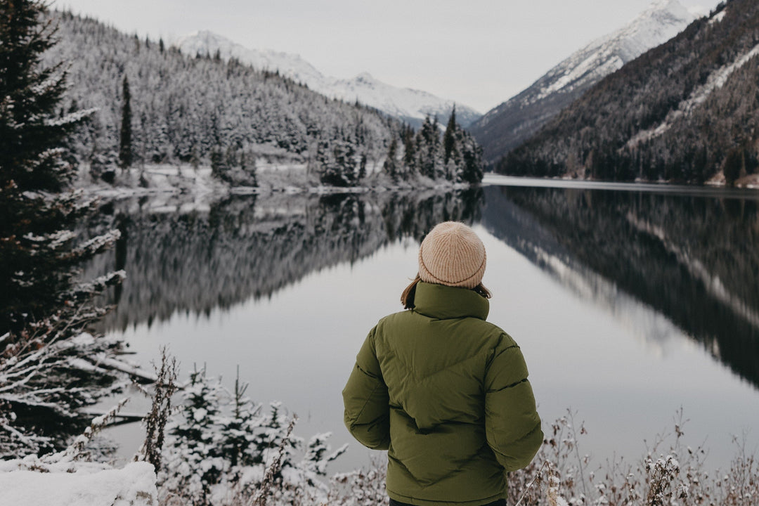 A woman standing in a snow covered mountain trail.
