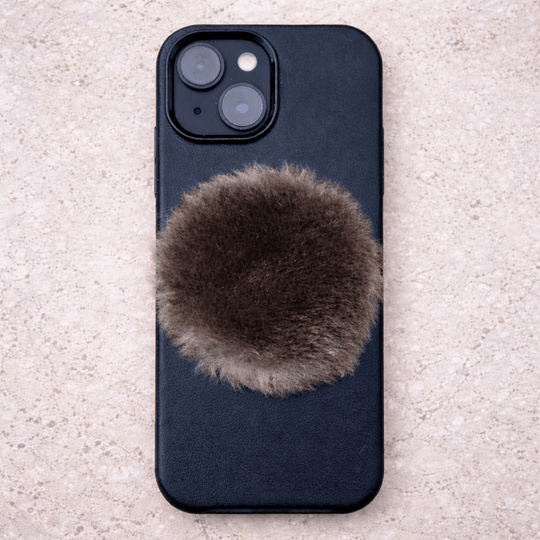 Phone case with a fluffy fur patch on a textured surface